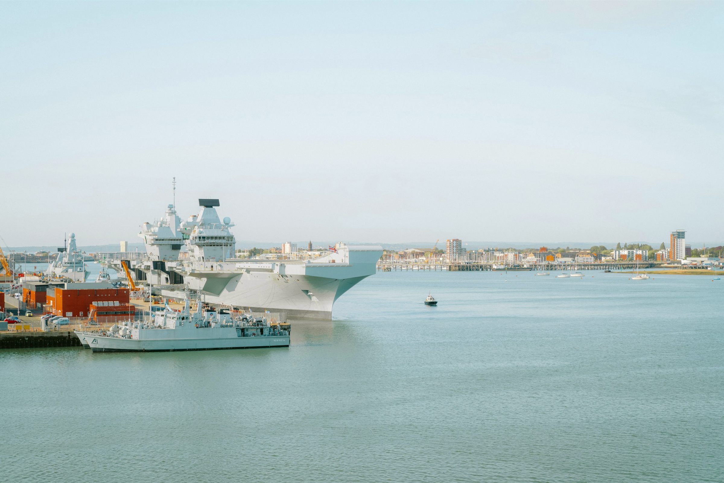 Aircraft carrier docked in harbour with city skyline