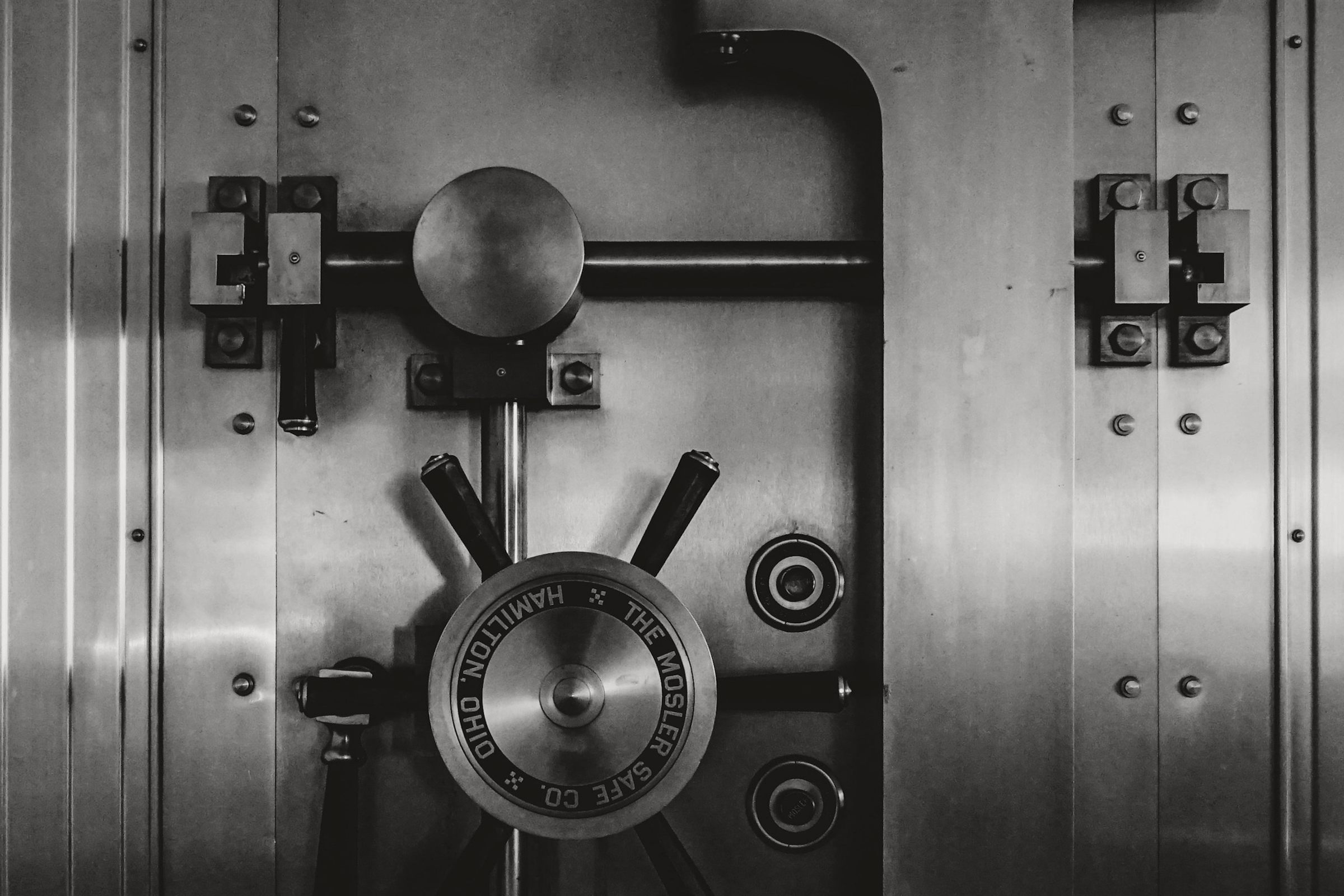Black and white steel bank vault door with locking wheel