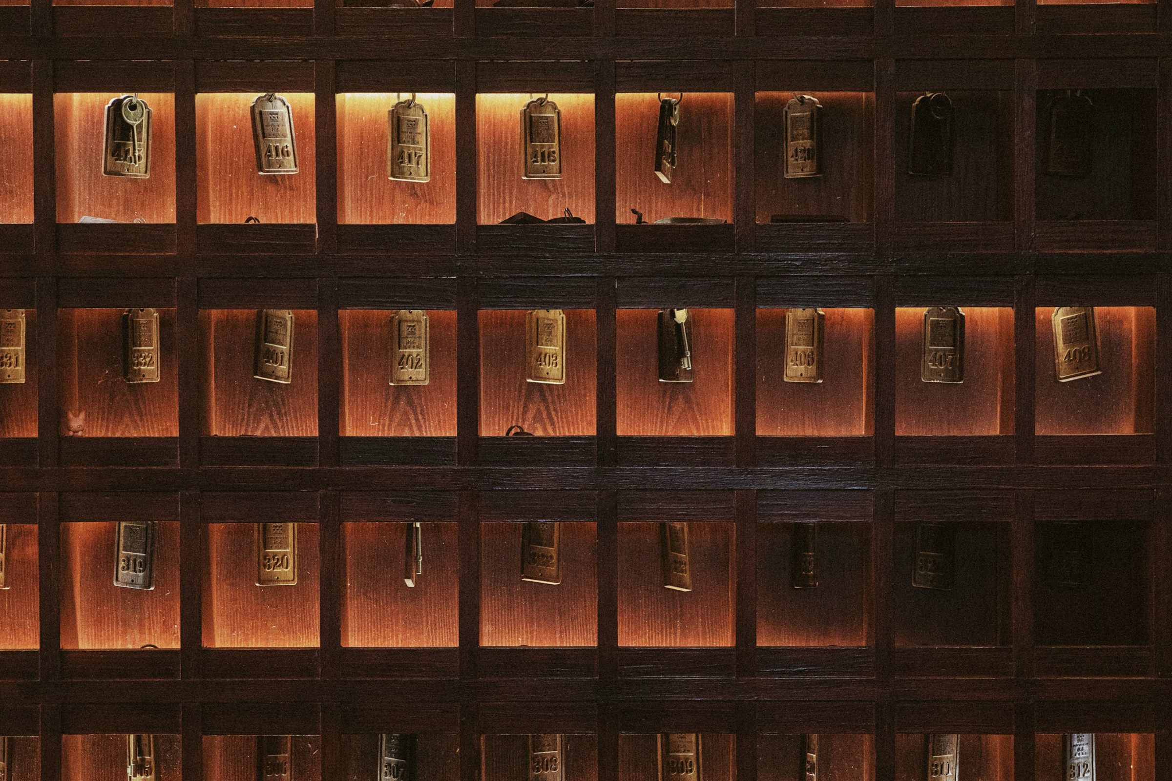 Wall of lit wooden key cubbies holding old room keys