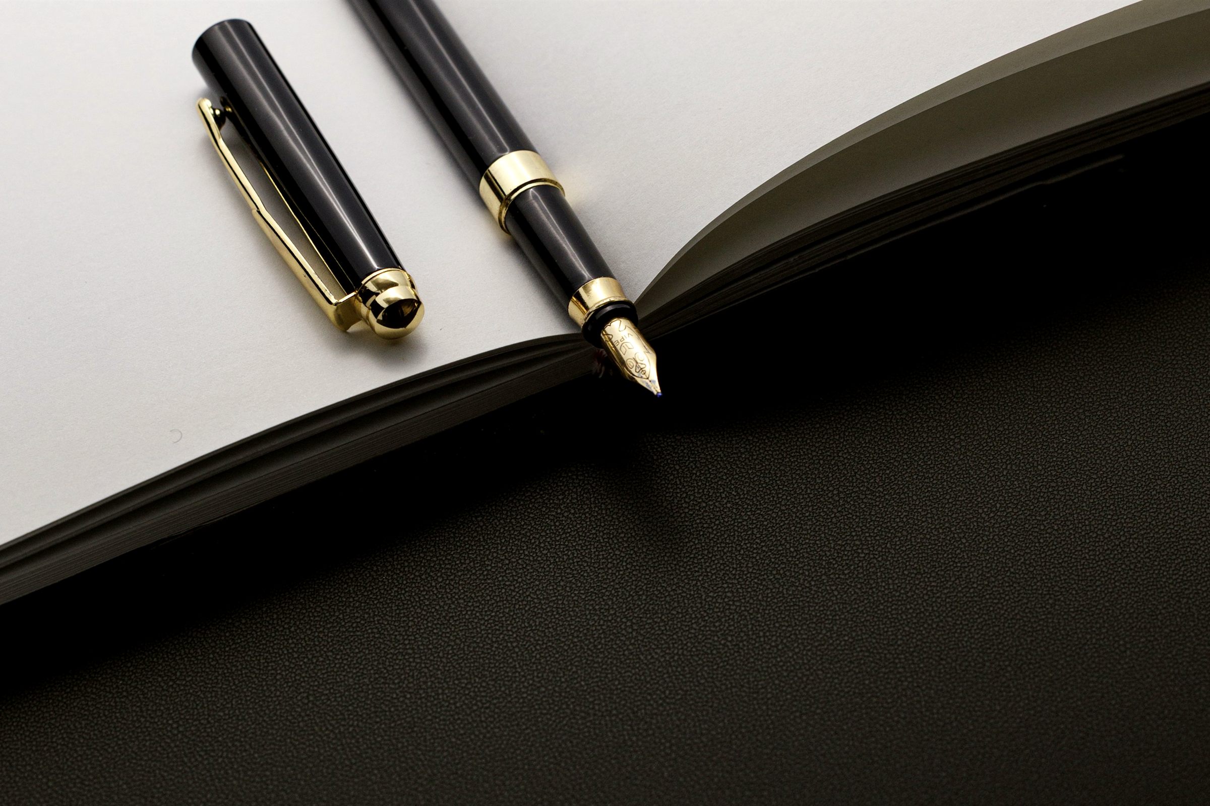 Black and gold fountain pens on an open notebook