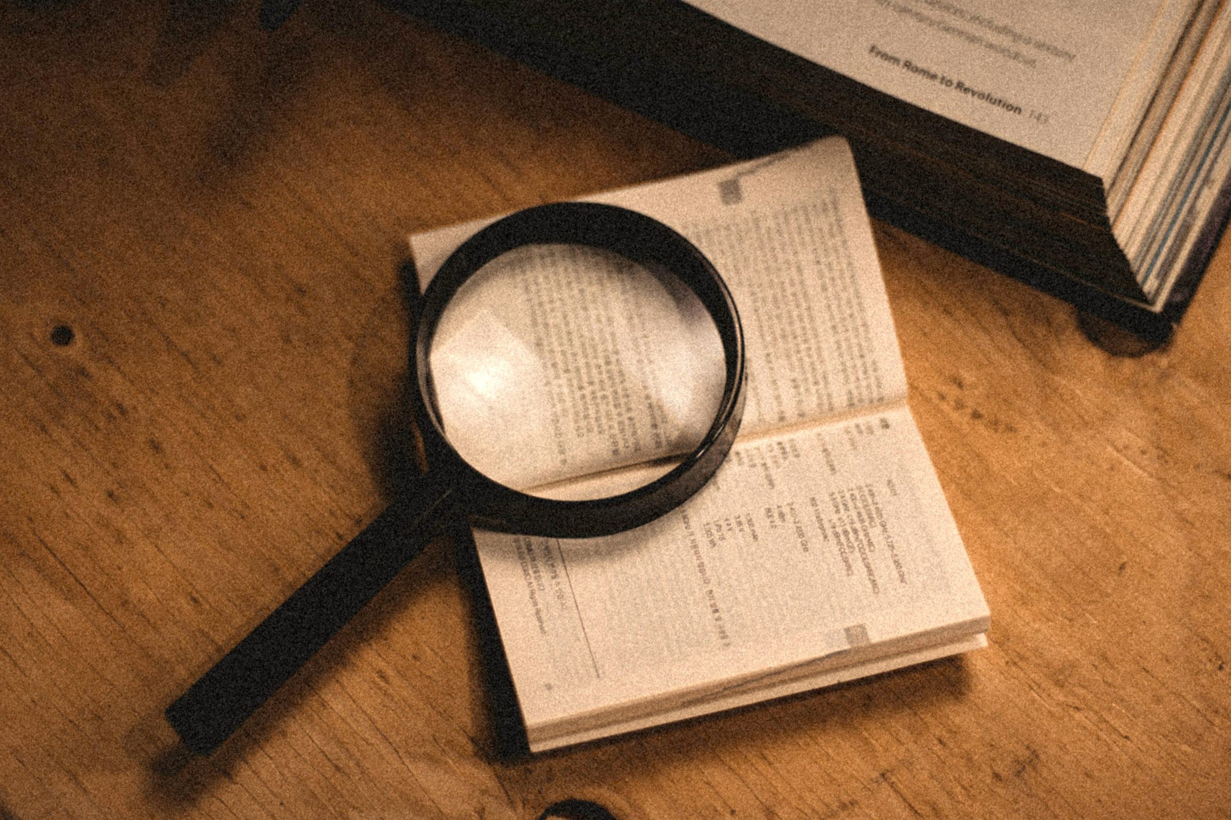 Magnifying glass on an open book on a wooden desk
