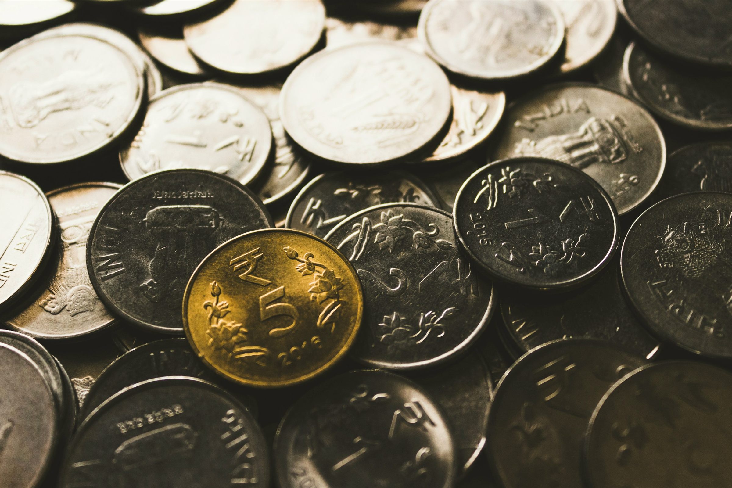 Close-up of a pile of silver coins with one gold coin