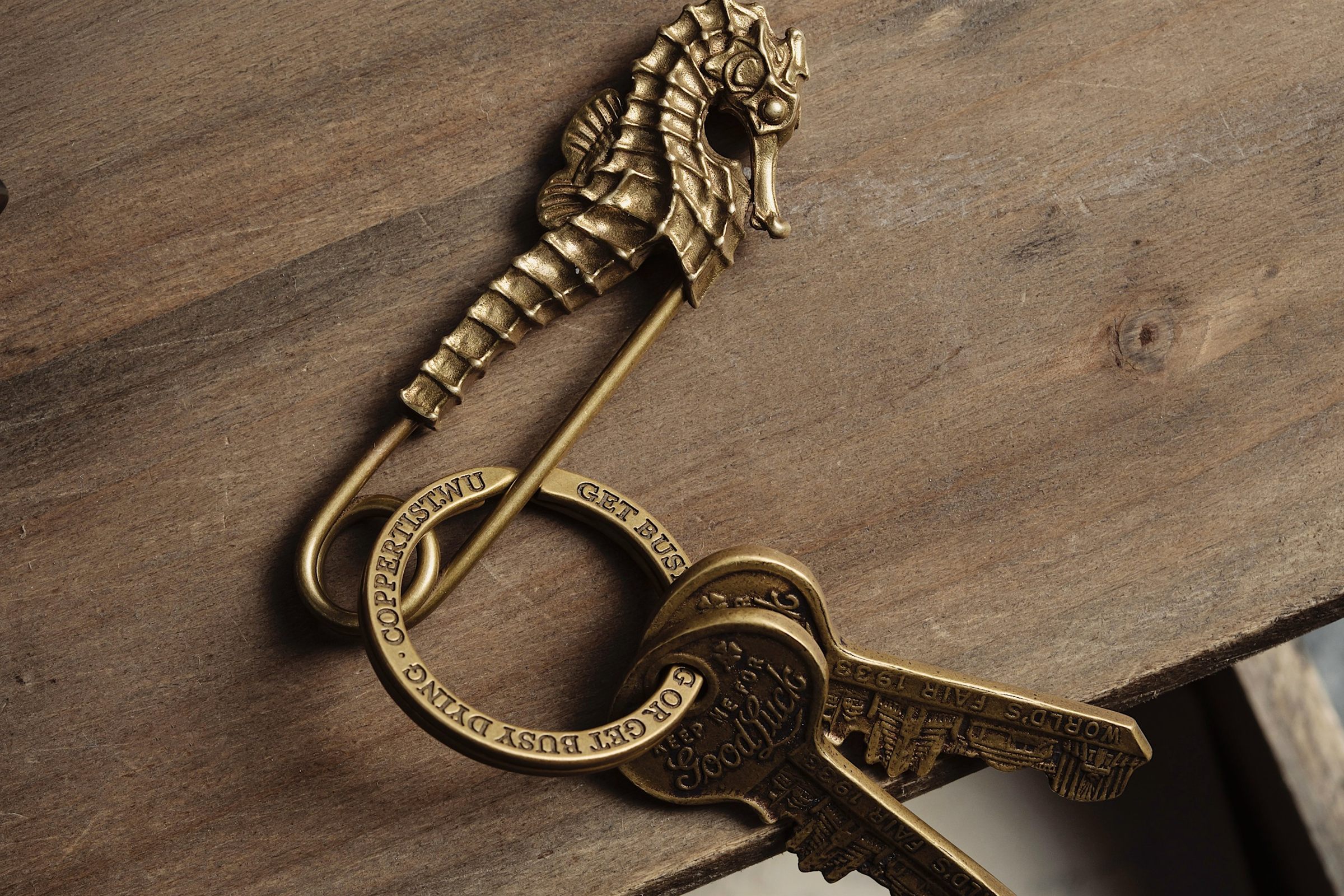 Brass keys on an ornate keyring resting on dark wood